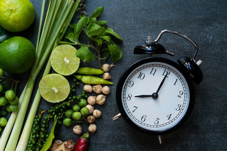 Clock lying next to fresh herbs and spices